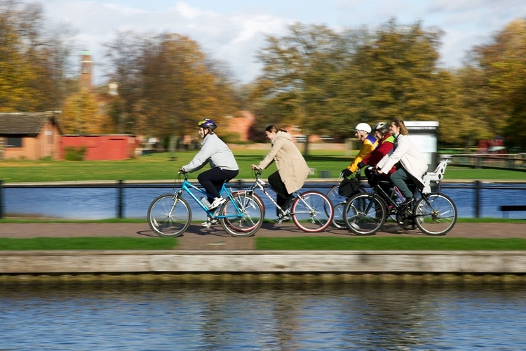 A photograph of five cyclists cycling along the towpath by Victoria Park in Newbury