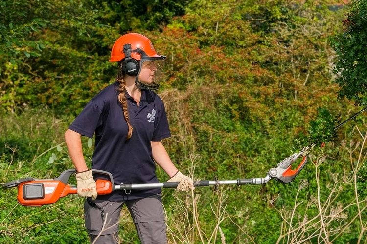 A photograph of one of our Rights of Way Rangers safely cutting back a bush using a hedge trimmer