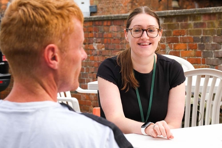 A photograph of two people talking sat outside across from one another