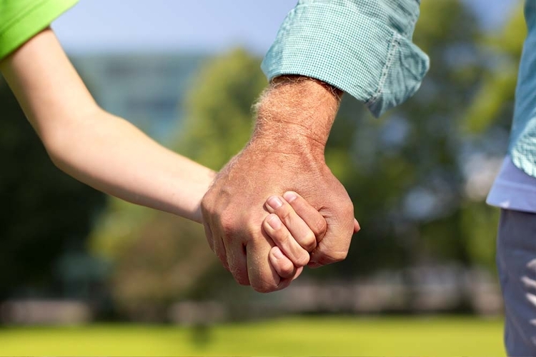 An image of a foster parent and a child holding hands