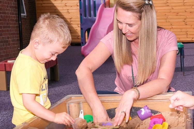Jobs and Careers in Children and Family Services An image of a woman and a child playing in a sand pit.