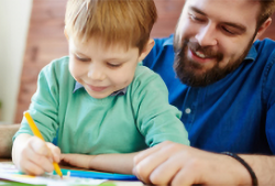 A parent helping his child with some colouring in.